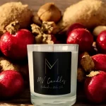 A clear glass container candle with cranberries and ginger in the background